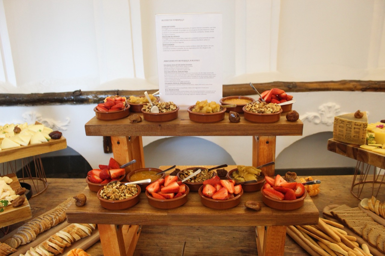 Buffet di formaggi con taglieri, frutta, miele e carta degli abbinamenti