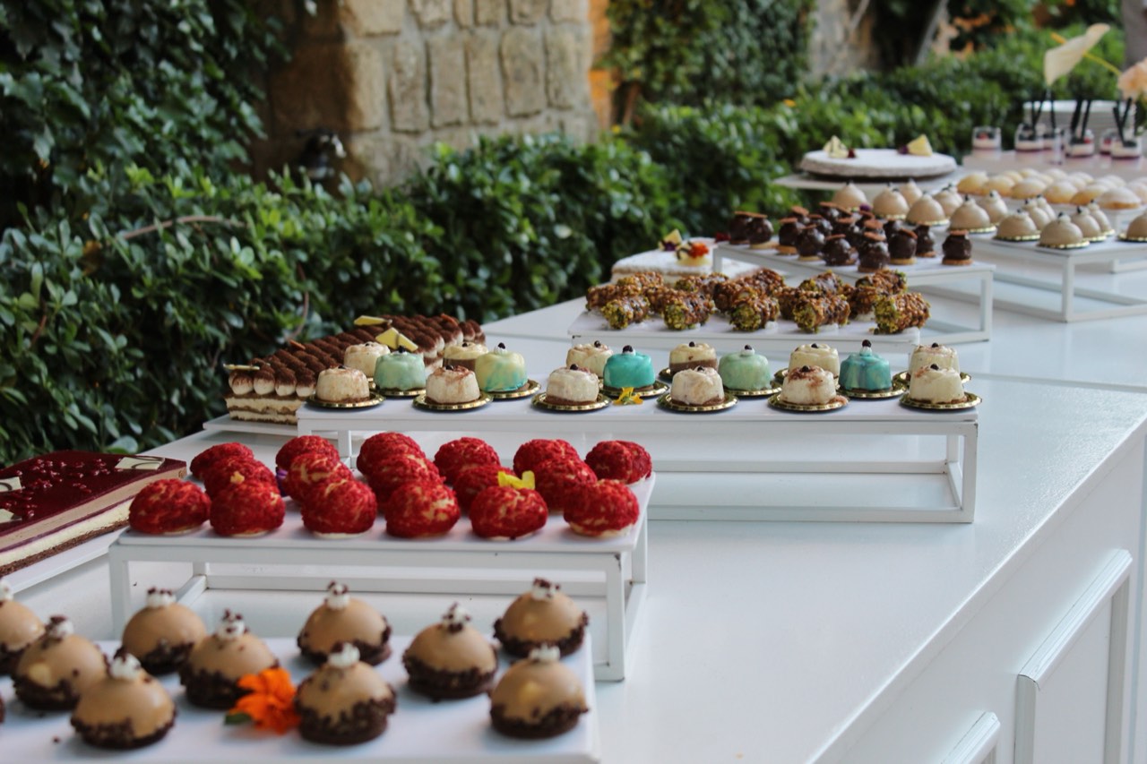 Mosaico di dolci al completo su alzate bianche, con torta e pasticceria mignon