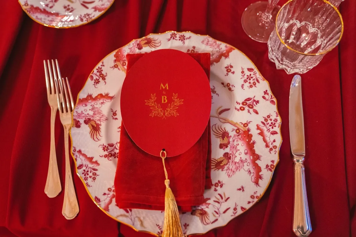 Mise en place natalizia con piatto decorato, tovagliolo rosso e monogramma degli sposi
