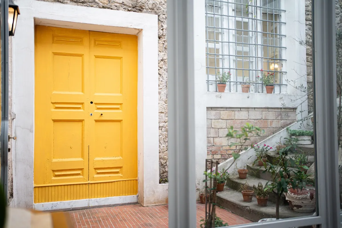 Porta gialla dell'ingresso dell'Antica Scuderia accanto a una finestra con inferriata
