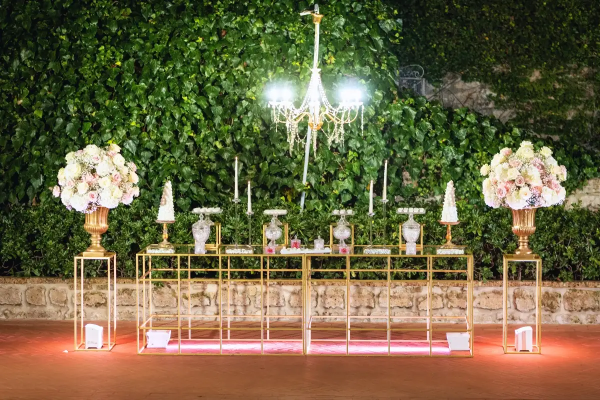 Confettata su tavoli dorati davanti al muro d'edera del giardino, con lampadario di cristallo e vasi di rose