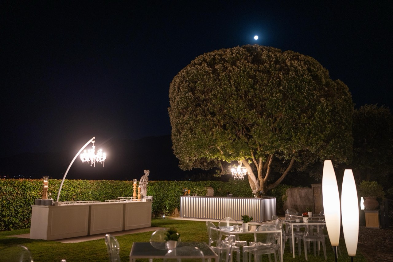 Buffet notturno in giardino con lampadario appeso all'albero e luna piena