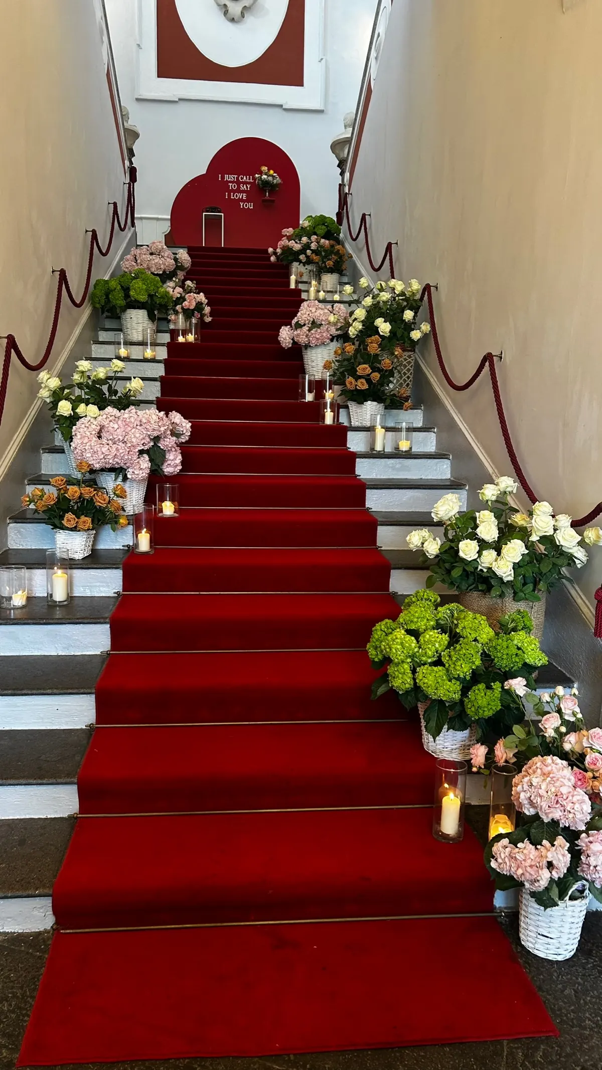 Scalone d'onore con passatoia rossa, ortensie e rose sui gradini e un cuore rosso in cima