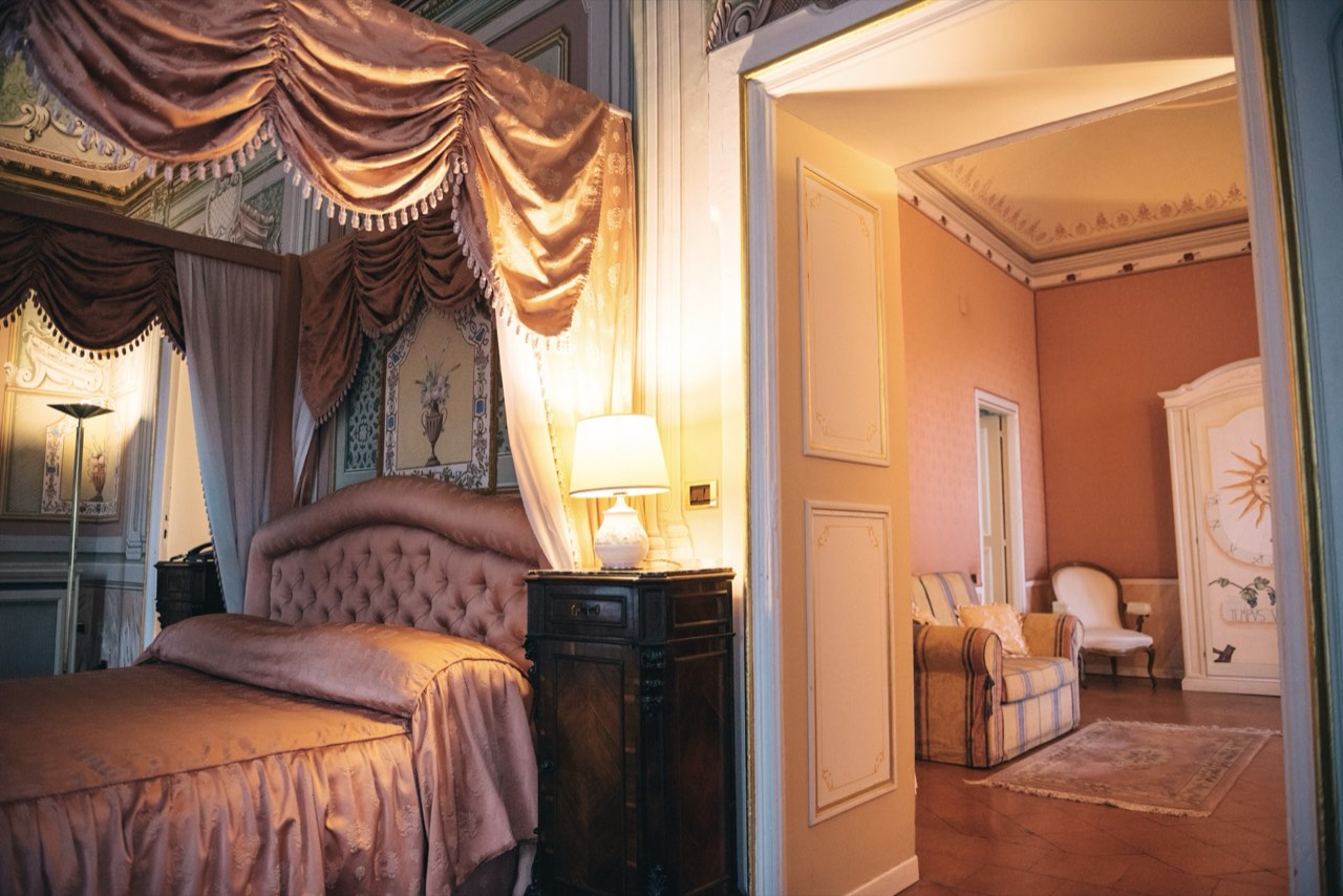 Suite di Villa Soglia con letto a baldacchino drappeggiato e stanza attigua oltre la porta