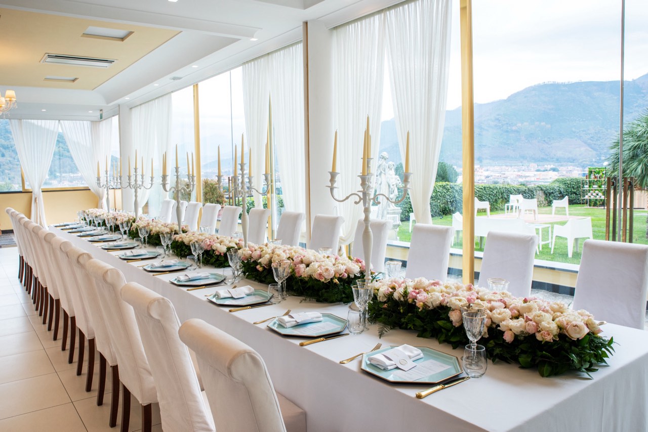 Tavolo imperiale allestito con candelabri e peonie nella sala interna