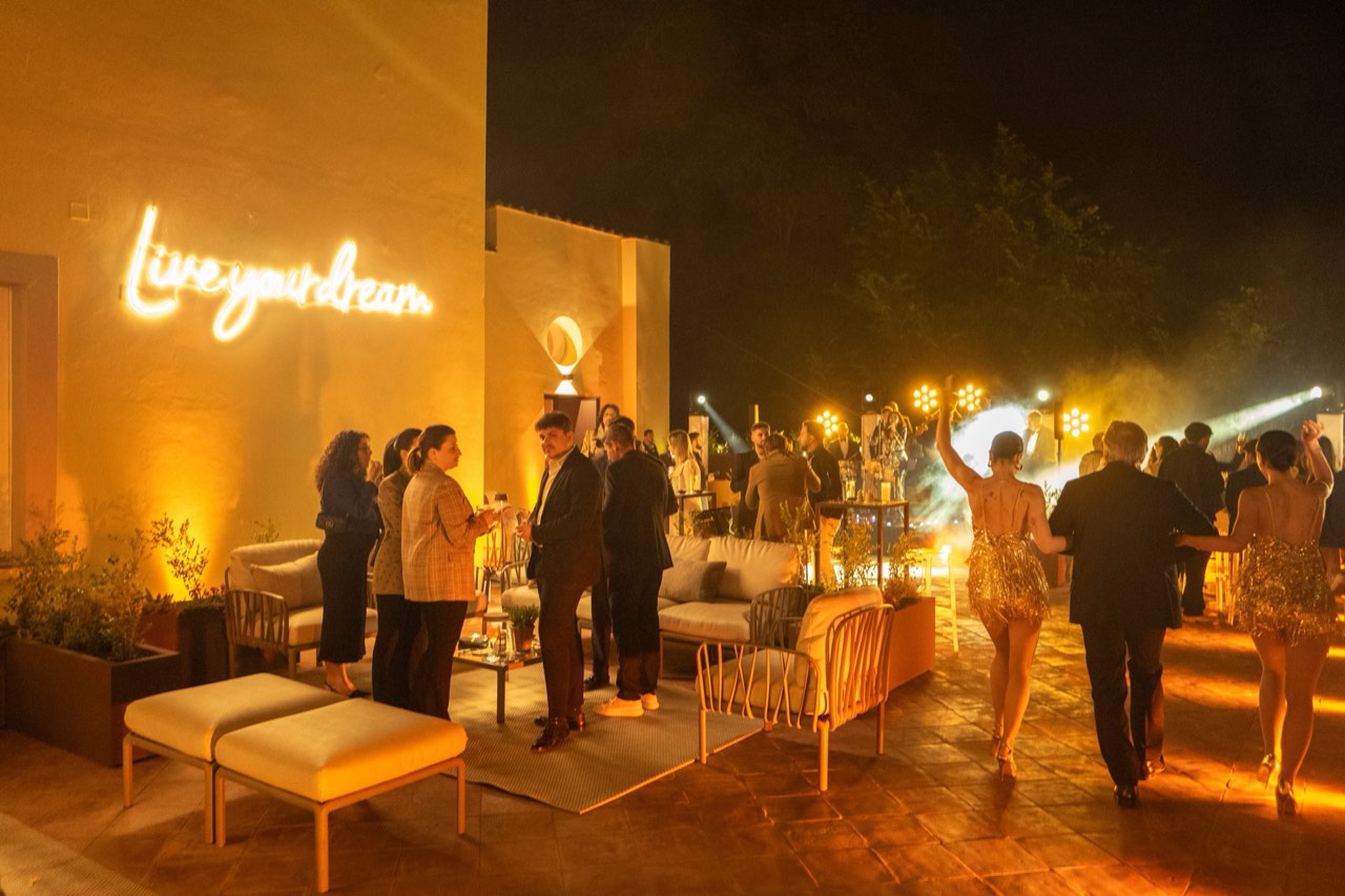 Serata sulla terrazza con l'insegna al neon Live your dream, la band dal vivo e gli ospiti